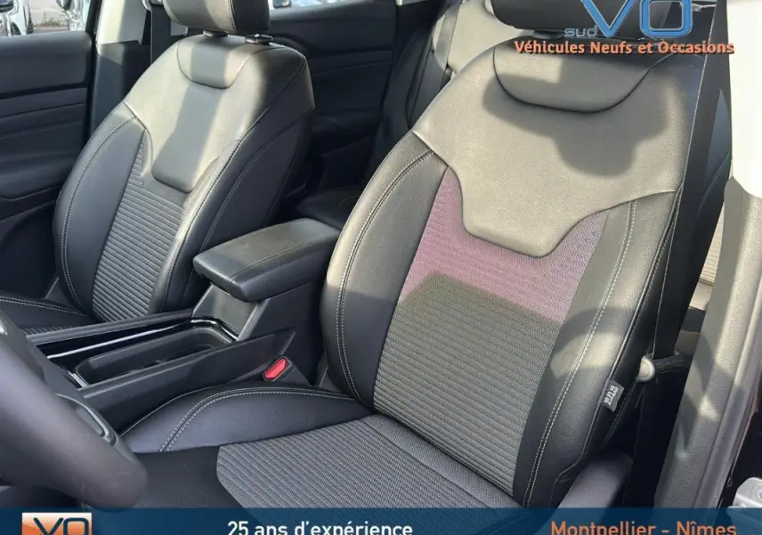 Gros plan sur les sièges avant en tissu et cuir noir du Jeep Compass 2024 avec accoudoir central visible.