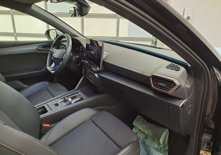 Vue intérieure côté conducteur de la CUPRA Leon 2025 avec tableau de bord moderne et finitions cuivrées.