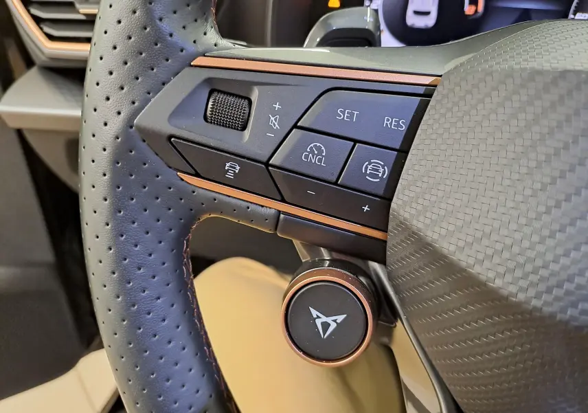 Gros plan sur le volant perforé noir avec commandes et logo CUPRA cuivré, intérieur du Leon Ph.2 2025.