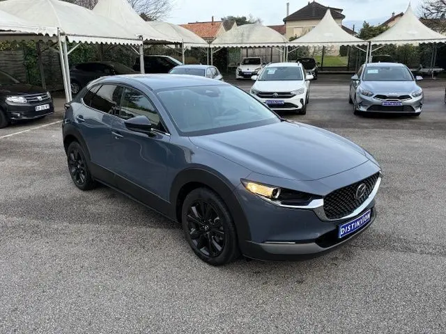 Vue 3/4 avant gauche d’un Mazda CX-30 2024 Polymetal Grey avec jantes noires et calandre distinctive.