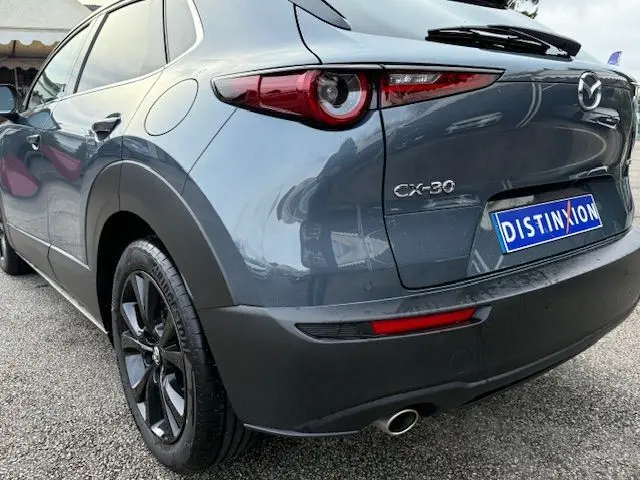 Vue 3/4 arrière droite d'un Mazda CX-30 2024 Polymetal Grey avec feux arrière ronds et jantes noires.