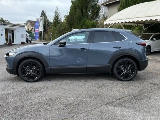 Vue de profil côté gauche d'un Mazda CX-30 2024 gris Polymetal avec jantes noires et détails noirs contrastants.