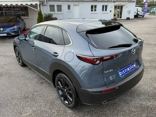Vue 3/4 arrière droite d’un Mazda CX-30 2024 gris Polymetal avec jantes noires et vitres teintées.