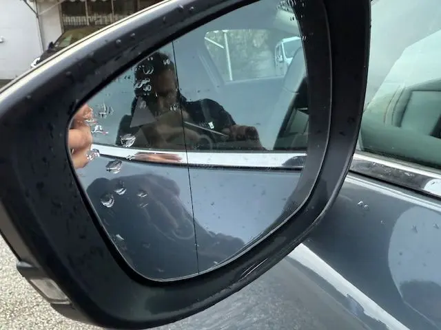 Gros plan sur le rétroviseur côté gauche du Mazda CX-30 2024 Polymetal Grey avec gouttes de pluie visibles.