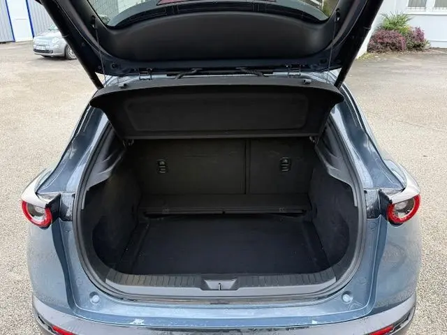Vue arrière ouverte du coffre d'un Mazda CX-30 2024 en Polymetal Grey, montrant l'espace de chargement vide.