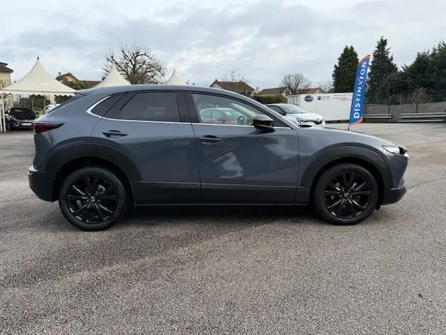 Vue de profil côté gauche d'un Mazda CX-30 2024 gris Polymetal avec jantes noires et lignes fluides distinctives.