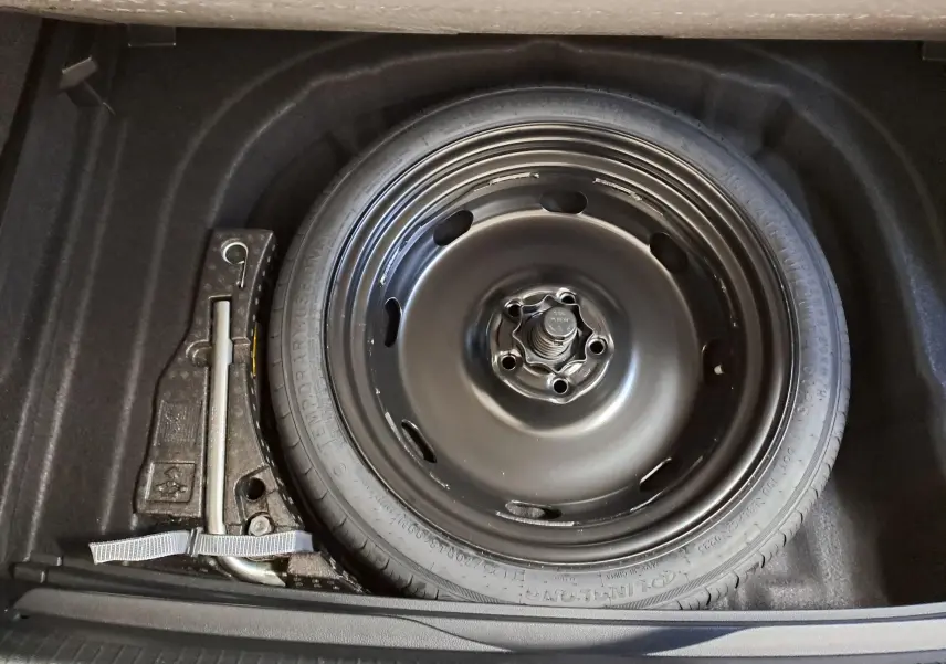 Vue plongeante sur la roue de secours noire et le cric dans le coffre d'une Volkswagen Golf 1.5 TSI 116 BVM6 Argent Dolomite.