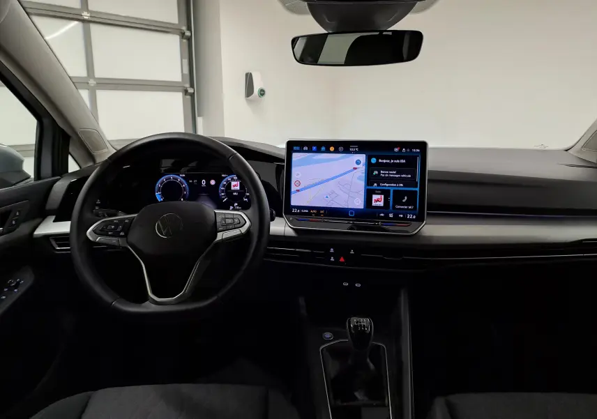 Vue intérieure frontale du poste de conduite de la Volkswagen Golf 1.5 TSI 2025 avec écran tactile et levier de vitesse manuel.
