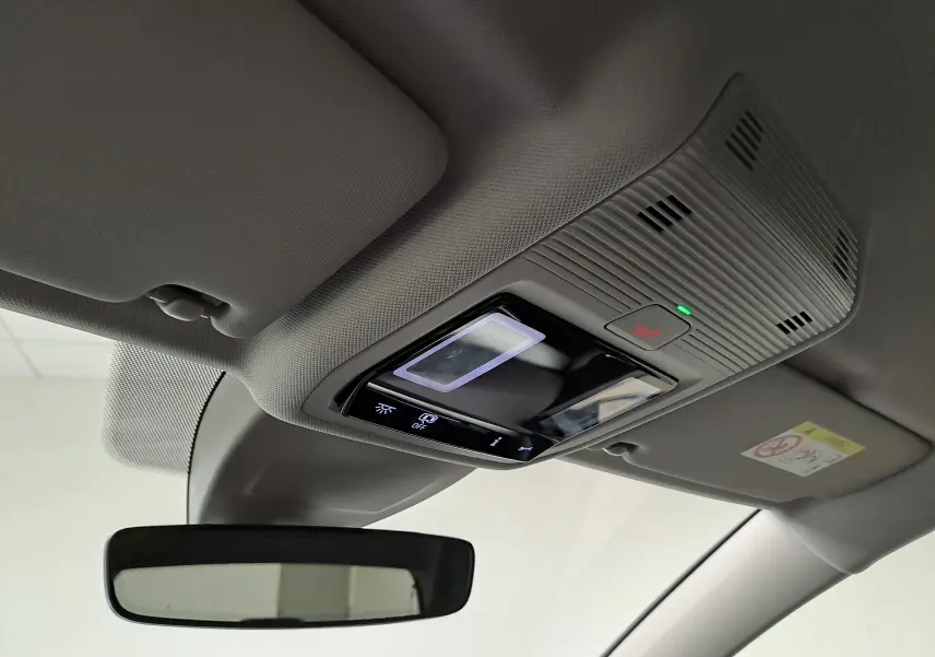 Vue intérieure en plongée du plafonnier gris clair avec commandes lumineuses et rétroviseur d’une Volkswagen Golf 2025.