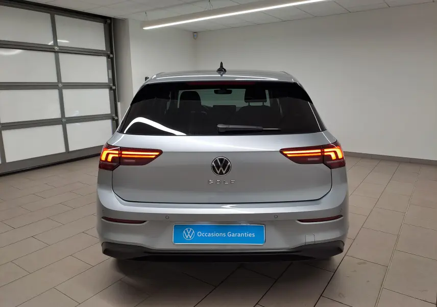 Vue arrière d'une Volkswagen Golf 1.5 TSI 116 BVM6 argent Dolomite avec feux allumés dans un garage.