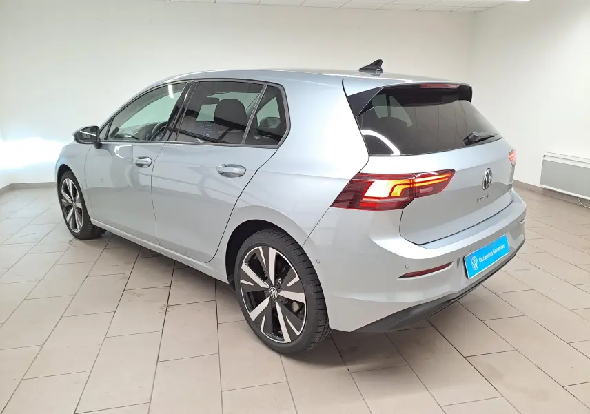 Volkswagen Golf 1.5 TSI 2025 vue 3/4 arrière côté gauche, peinture argent Dolomite et jantes alliage 18 pouces.