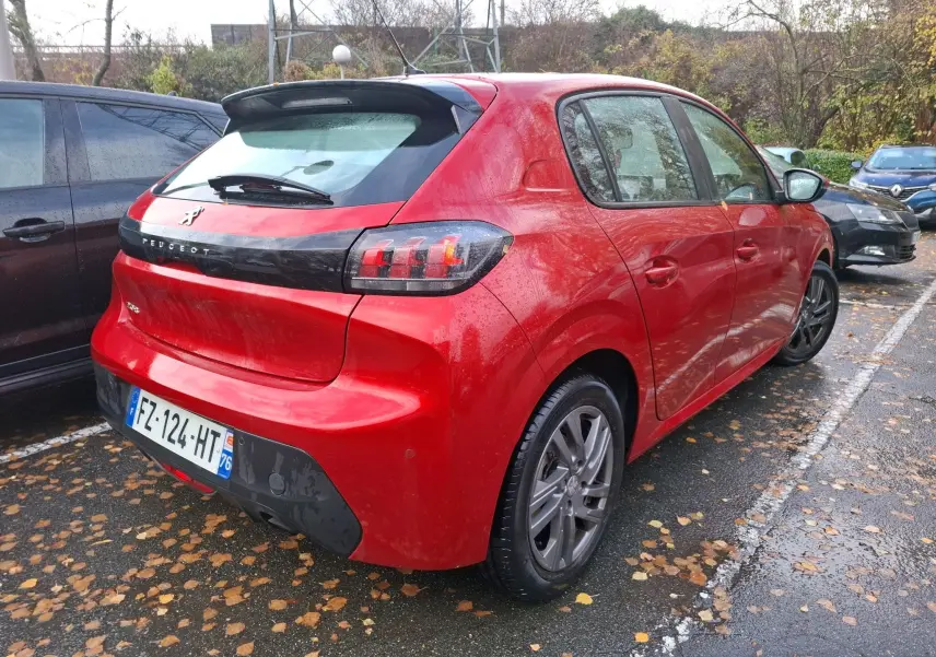 Vue 3/4 arrière droite d'une Peugeot 208 rouge Elixir 2021 garée, avec feux arrière à effet griffes et jantes alliage.