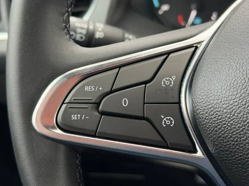 Gros plan sur les commandes du régulateur de vitesse au volant cuir du Nissan Townstar blanc minéral 2024.