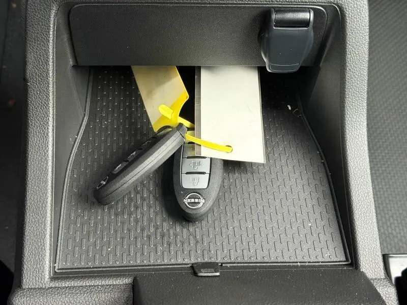 Gros plan sur la console centrale avec deux clés Nissan posées sur un tapis antidérapant noir.