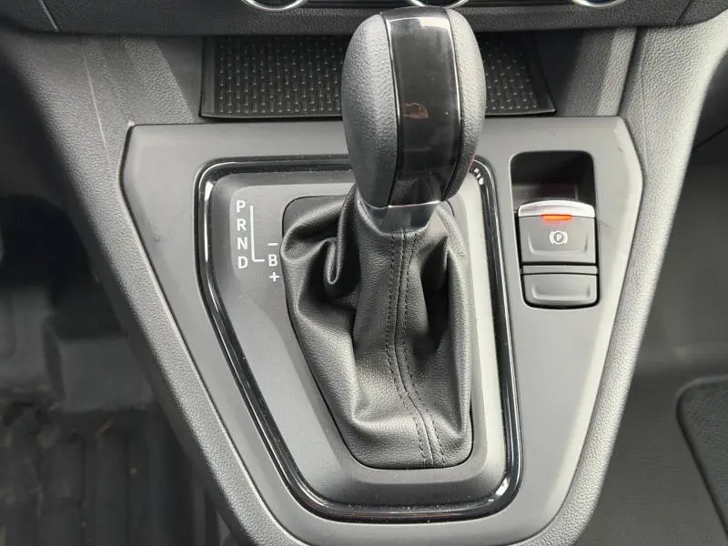 Gros plan sur la commande de boîte automatique cuir noir du Nissan Townstar L1 EV 2024 avec frein à main électronique activé.