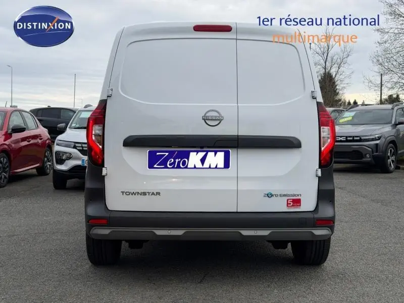 Vue arrière d'un Nissan Townstar blanc minéral électrique avec portes battantes et logo Zero Emission visible.