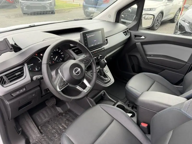 Vue intérieure côté conducteur du Nissan Townstar blanc Minéral 2024, avec tableau de bord moderne et écran tactile central.