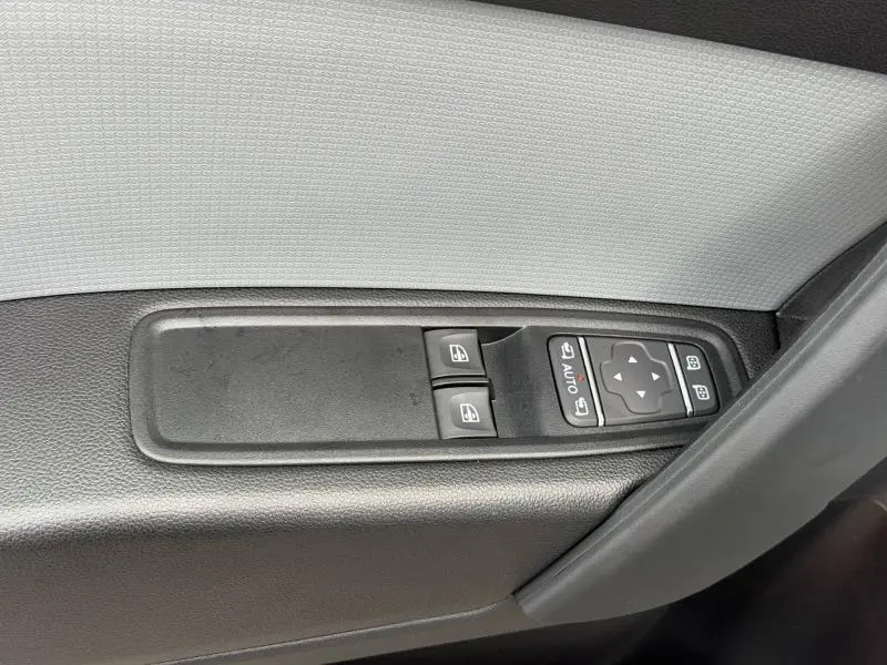 Gros plan sur les commandes des vitres électriques et rétroviseurs du côté gauche d'une Nissan Townstar blanc minéral 2024.