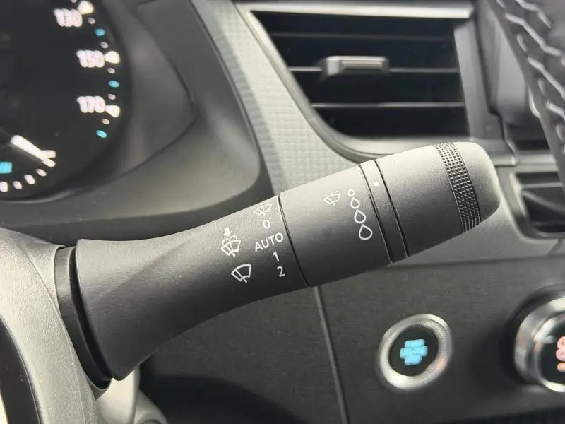 Gros plan sur la commande des essuie-glaces à gauche du volant dans l'habitacle du Nissan Townstar blanc 2024.