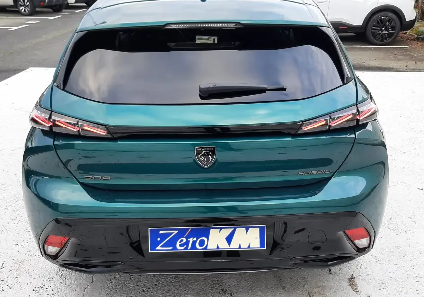 Vue arrière d'une Peugeot 308 hybride bleu Lagoa avec feux LED distinctifs et vitrage arrière teinté.
