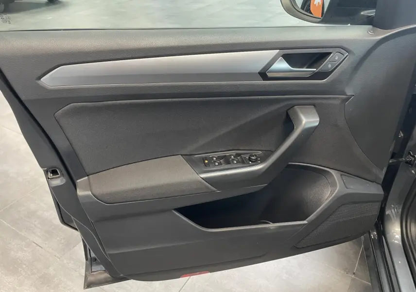 Vue rapprochée de la porte avant gauche du Volkswagen T-Roc Indium Gray, avec commandes électriques et insert argenté.