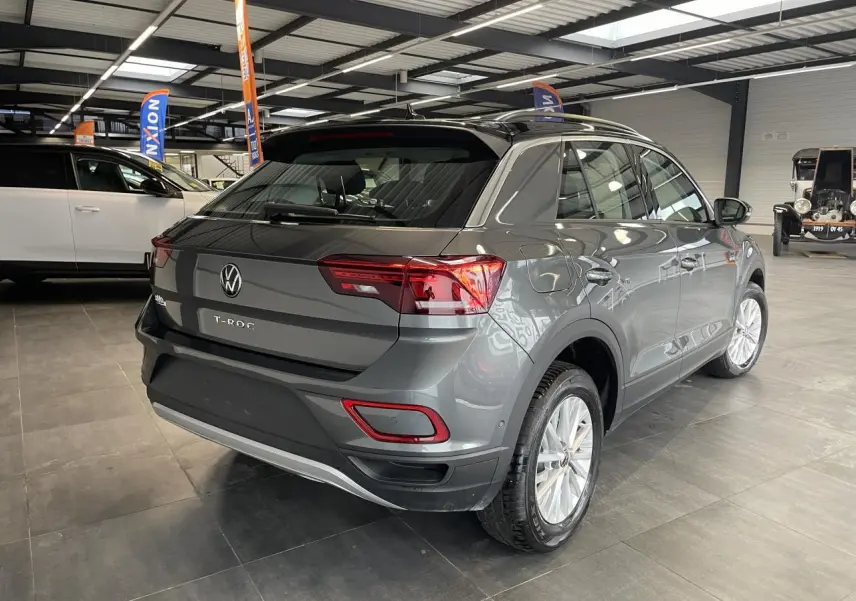 Vue 3/4 arrière droite du Volkswagen T-Roc gris Indium métallisé avec toit noir en intérieur d'exposition.