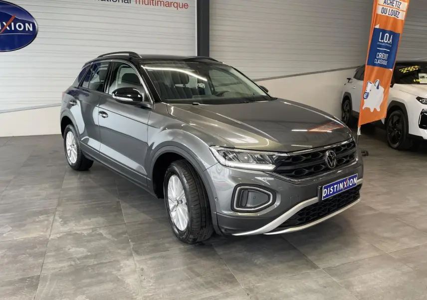 Volkswagen T-Roc gris Indium en 3/4 avant droit, avec toit noir et jantes alliage 16 pouces en showroom.
