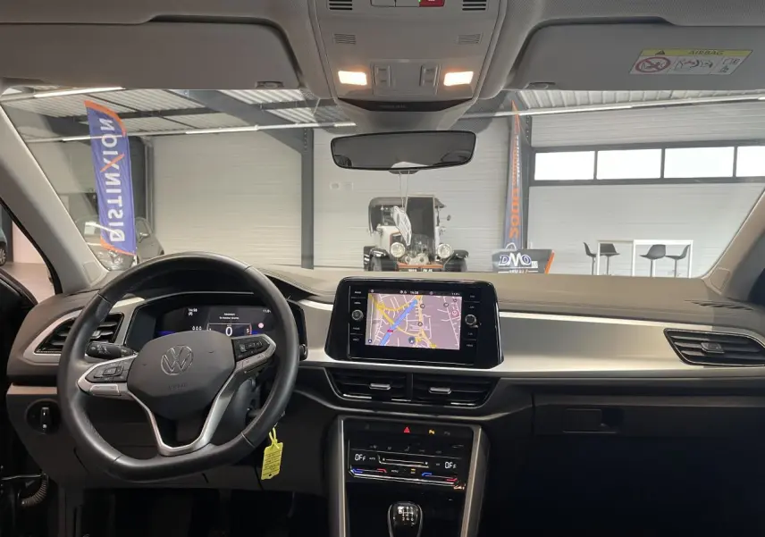 Vue intérieure frontale du tableau de bord du Volkswagen T-Roc 2025 gris Indium avec écran tactile et volant multifonction cuir.