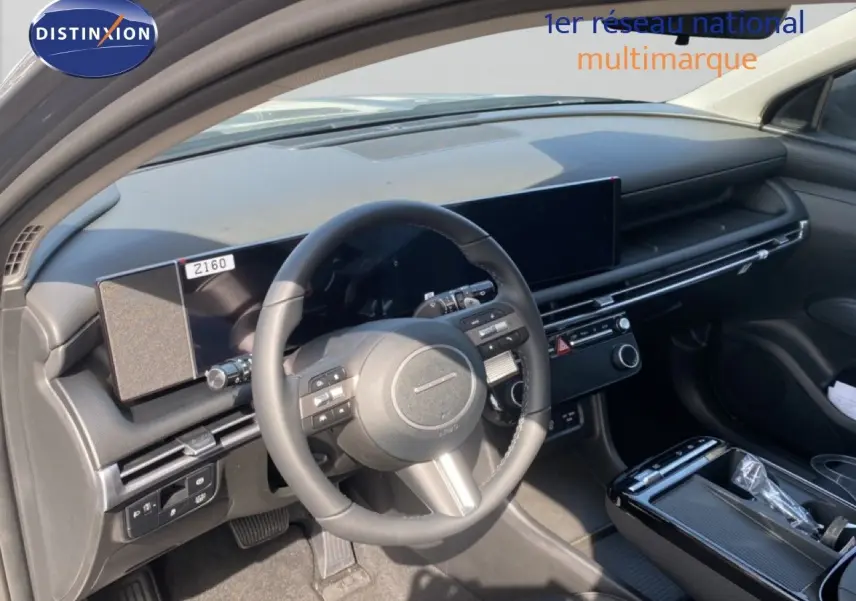 Vue intérieure côté conducteur du Hyundai Tucson 2026, tableau de bord moderne avec écran large et volant multifonction noir.