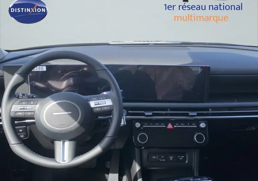 Vue intérieure du tableau de bord et volant noir du Hyundai Tucson 2026 gris Ecotronic, avec écran tactile large et commandes intégrées.