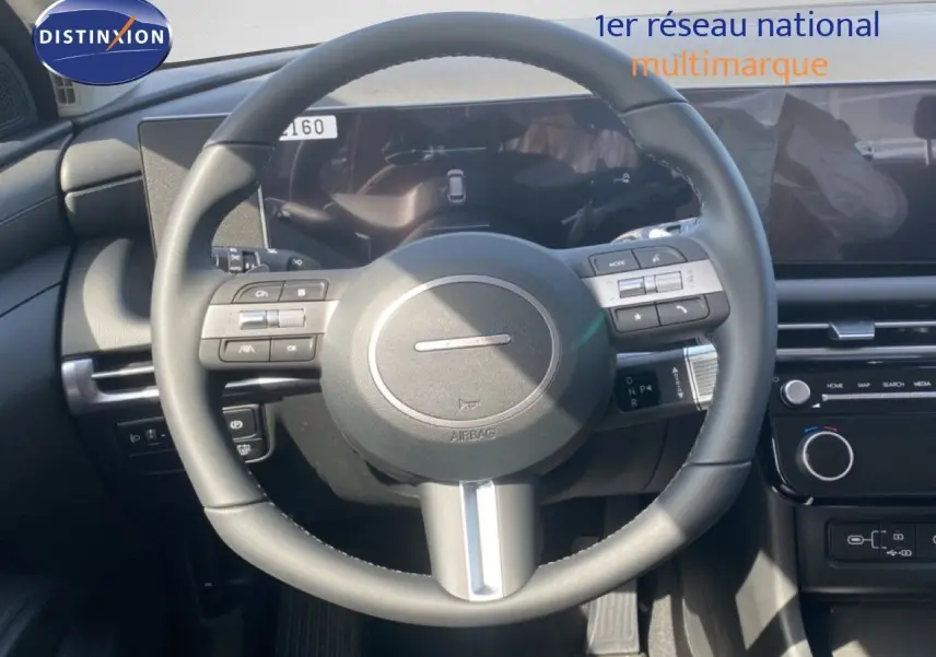 Vue rapprochée du volant multifonction noir et du tableau de bord digital du Hyundai Tucson gris Ecotronic Metal 2026.
