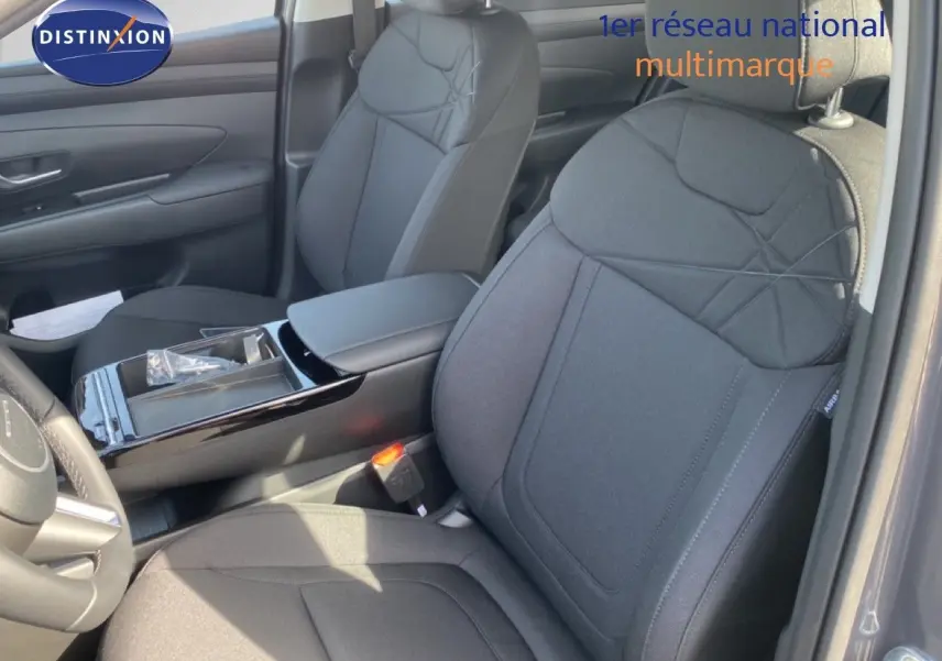 Vue intérieure côté conducteur du Hyundai Tucson 2026 gris Ecotronic, sièges tissu noir avec console centrale brillante.