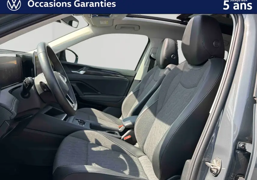 Intérieur avant du Volkswagen Tiguan gris 2025, vue côté droit sur les sièges tissu et cuir avec toit panoramique ouvert.