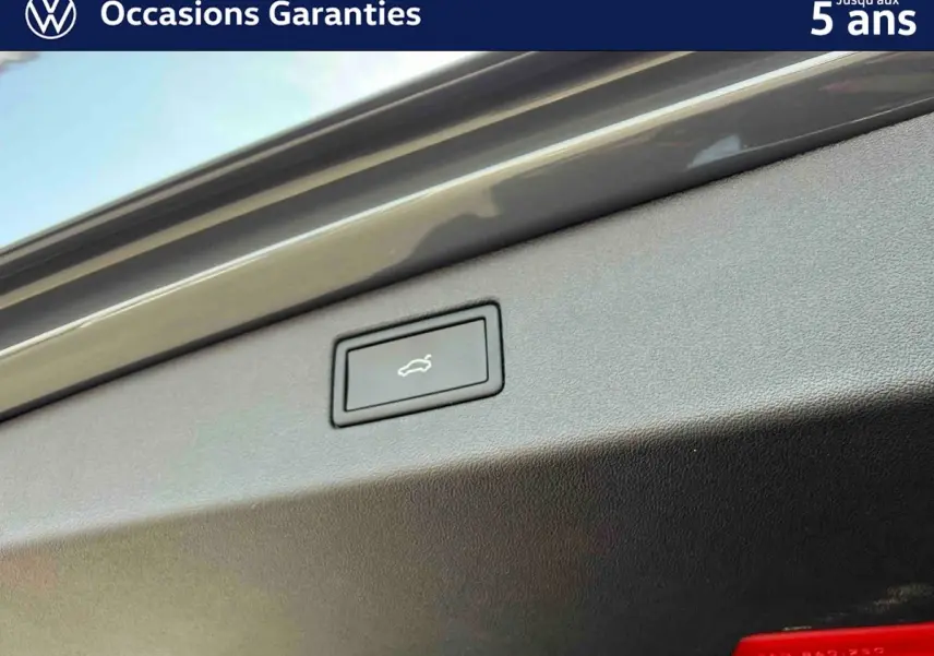 Bouton d'ouverture électrique du coffre sur la partie intérieure du hayon d'un Volkswagen Tiguan gris.