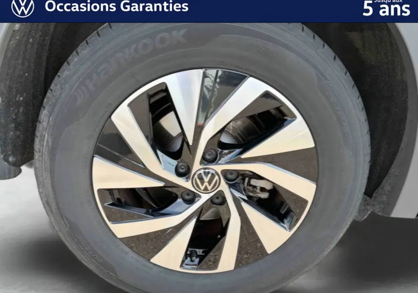 Gros plan sur la jante alliage Venezia noire et brillante du Volkswagen Tiguan gris, mettant en valeur le logo VW central.