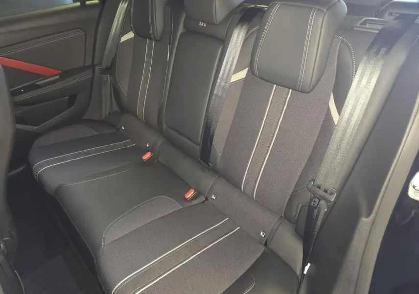 Vue intérieure de la banquette arrière noire de l'Opel Astra Hybrid 2024 avec ceintures et appuie-têtes intégrés.