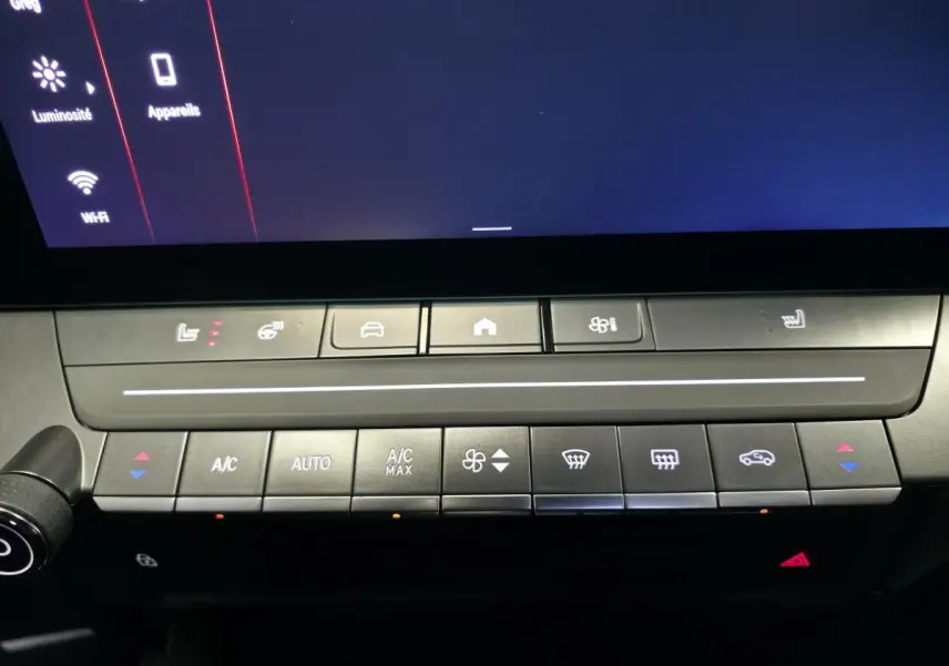 Détail de la console centrale de l’Opel Astra Hybrid 2024 avec commandes climatisation et écran tactile noir.