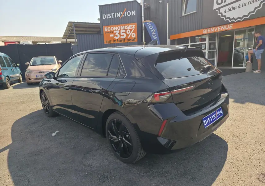 Vue 3/4 arrière droite de l'Opel Astra Hybrid noire avec jantes alliage noires et vitres surteintées.