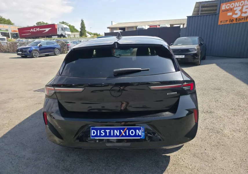 Vue arrière d'une Opel Astra Hybrid noire avec feux LED fins et logo Opel noir sur un parking extérieur.