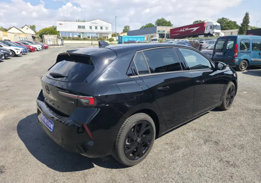 Opel Astra Hybrid 2024 noire en 3/4 arrière droit avec jantes alliage noires et vitres surteintées.