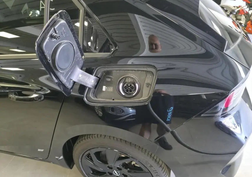 Prise de recharge ouverte sur le côté gauche arrière d’une Opel Astra Hybrid noire avec jantes alliage noires.