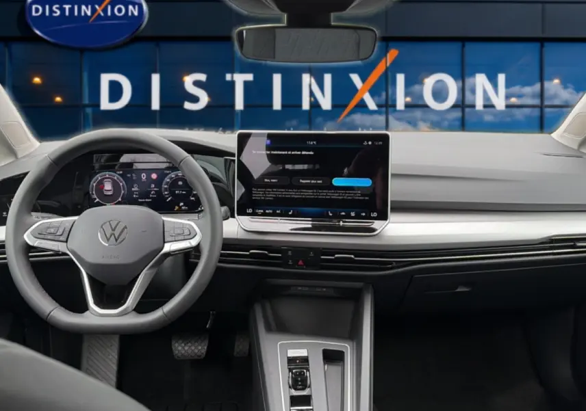 Vue intérieure avant du tableau de bord et volant gris clair d'une Volkswagen Golf 2026 avec écran tactile central et affichage numérique.