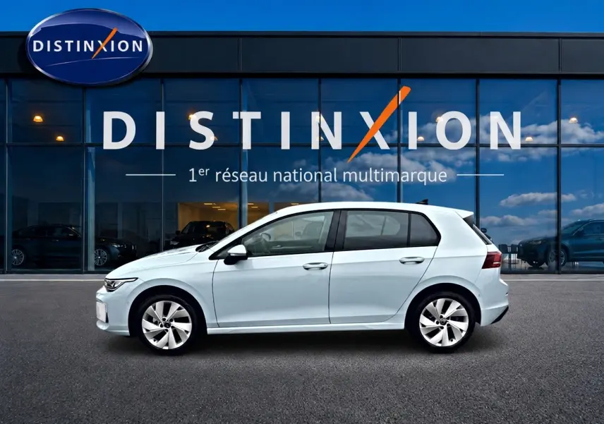 Profil droit d'une Volkswagen Golf 1.5 etsi evo2 116 life dsg7 bleu glacier, stationnée devant une vitrine Distinxion.
