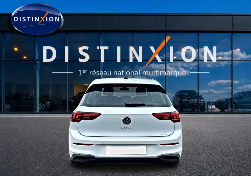 Vue arrière d'une Volkswagen Golf 1.5 etsi evo2 116 life dsg7 blanche, garée devant une vitrine Distinxion.