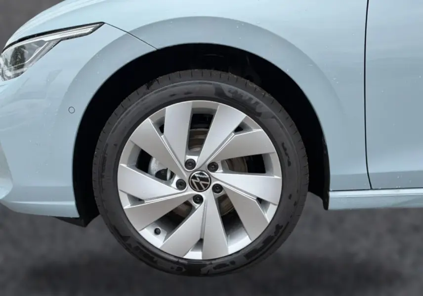 Gros plan sur la roue avant gauche et l'aile d'une Volkswagen Golf bleu glacier avec jante alu 17 pouces.