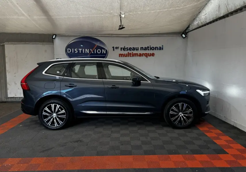 Vue de profil droit d'un Volvo XC60 bleu hybride rechargeable, avec jantes alliage et feux arrière distinctifs en forme de L.