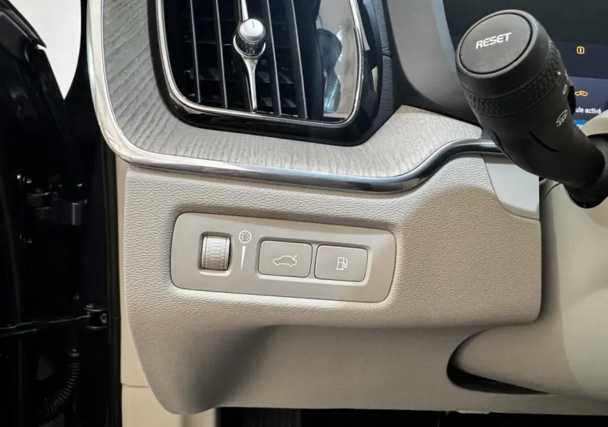 Détail intérieur côté gauche du tableau de bord beige clair du Volvo XC60 bleu avec commandes ouverture coffre et réservoir.