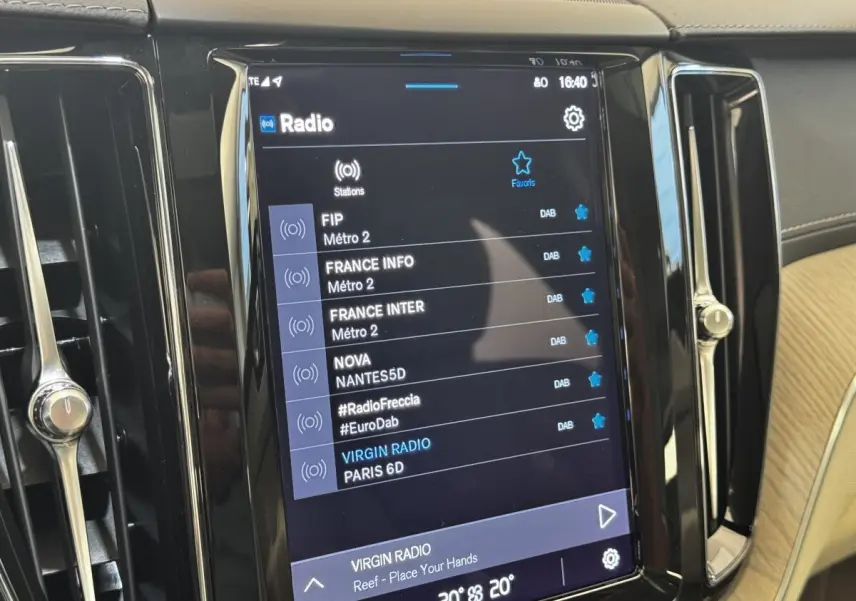 Écran tactile central du tableau de bord du Volvo XC60 bleu, affichant les stations radio numériques.