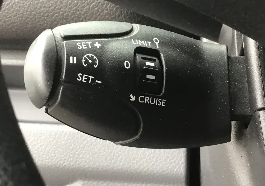 Gros plan sur la commande de régulateur de vitesse noire dans l'habitacle de l'Opel Vivaro blanc 2022.