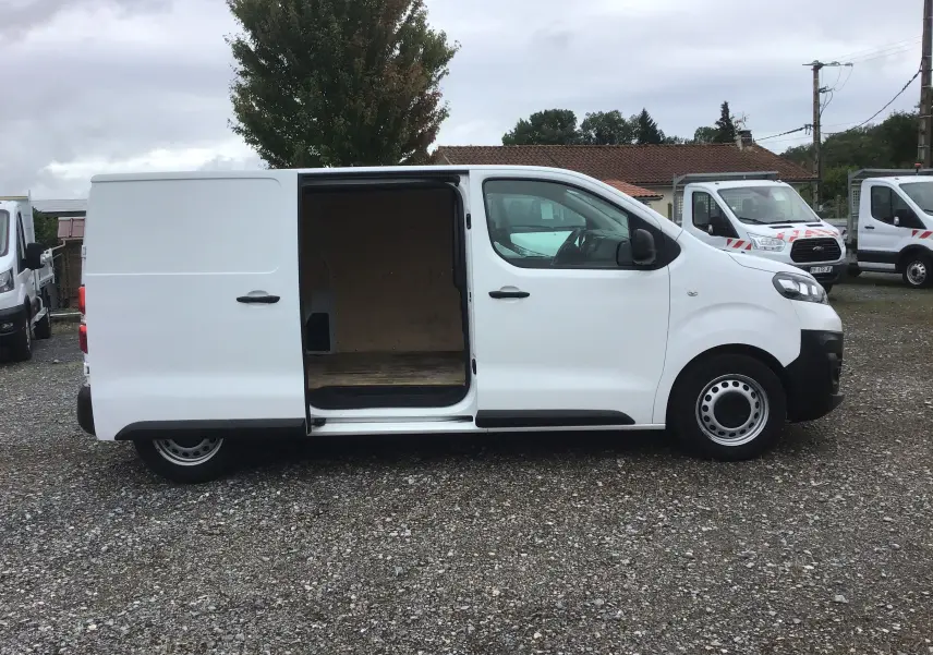 Vue de profil côté droit d'un Opel Vivaro blanc 2022 avec porte latérale coulissante ouverte montrant l'espace de chargement.